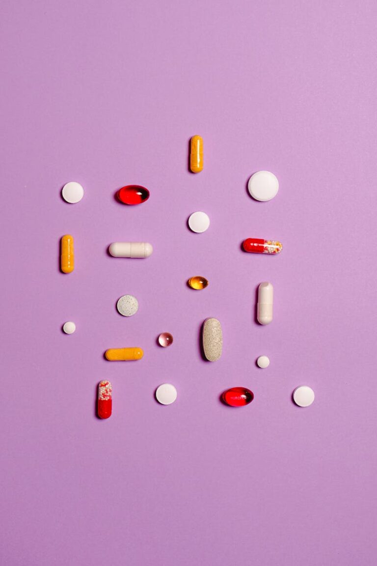 Variety of pills and capsules arranged on a purple surface, showcasing different medications.