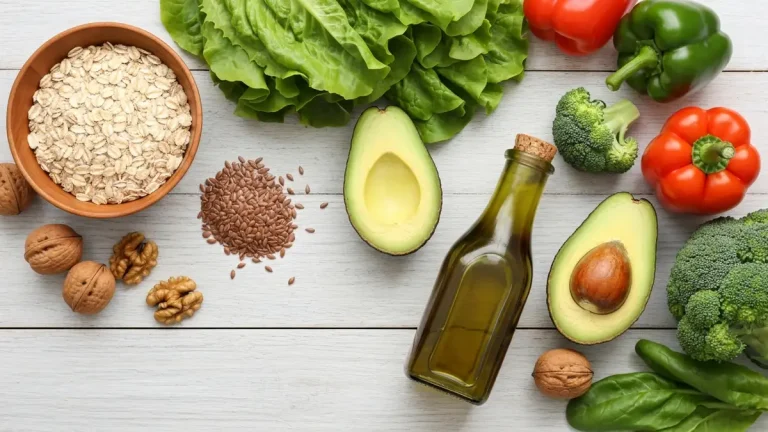 Produkty obniżające cholesterol: owies, orzechy, awokado i oliwa z oliwek na drewnianym stole